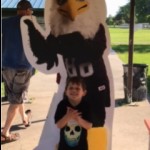 Child poses in front of Auggie Eagle standup